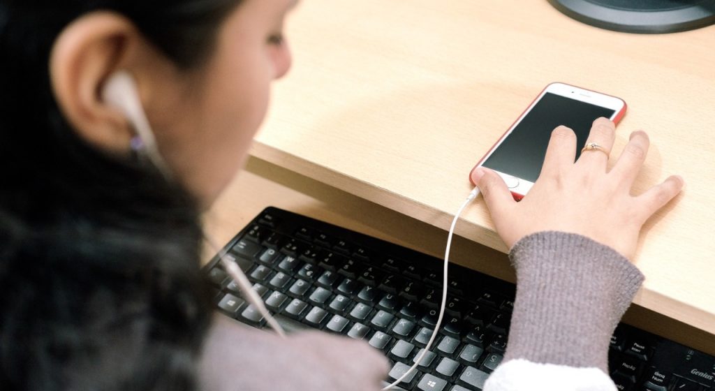 En la imagen se ve a una mujer joven que accede a un texto desde su teléfono celular mediante una audiodescripción. / Foto: Tiflonexos