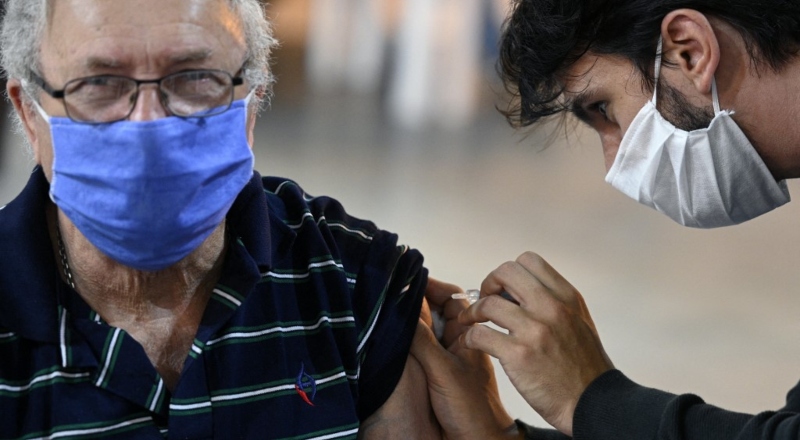 Un hombre mayor con barbijo recibe la vacuna.