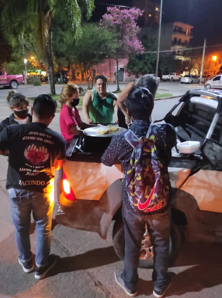 Voluntarios, alrededor de una olla, ayudan a personas en situación de calle.