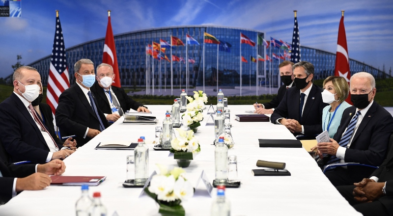 Líderes de la OTAN reunidos alededor de una mesa, con banderas de fondo.