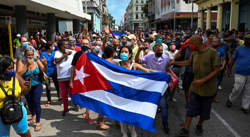 Ciudadanos cubanos en la calle, sostienen una bandera del país.