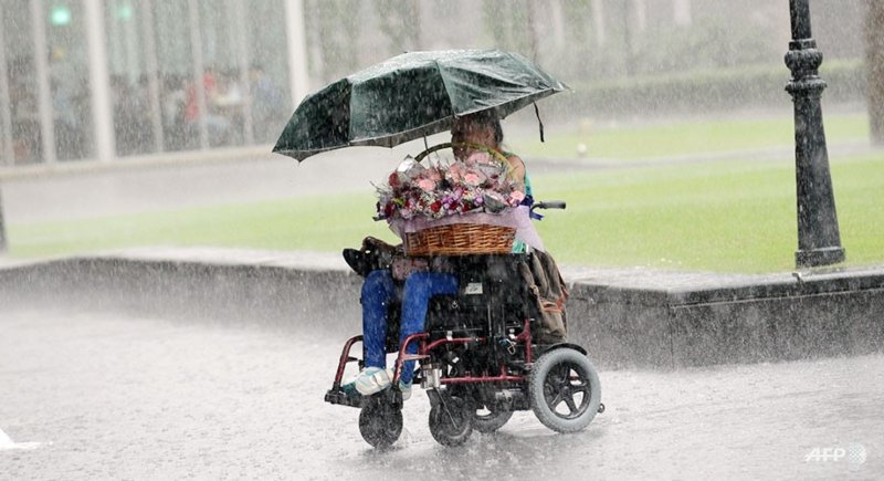 Una persona en silla de ruedas sostiene un paraguas bajo una gran tormenta.