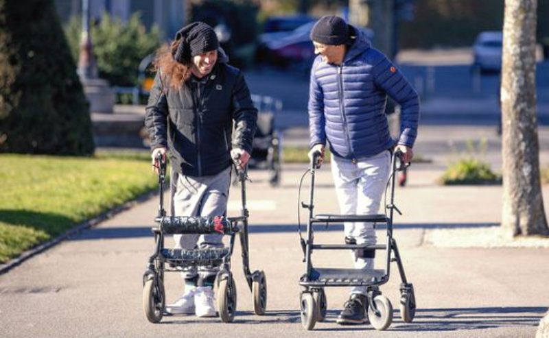 Dos personas parapléjicas caminando con andadores.