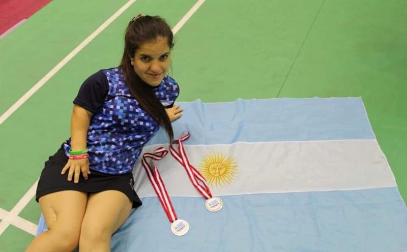 Karen posa con dos medallas y una bandera argentina.